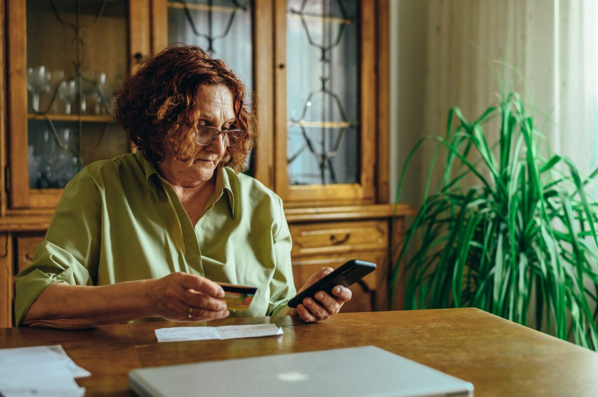 Senior with a smartphone and her credit card 1200x798